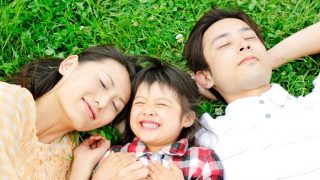 芝生に寝転ぶ三人家族