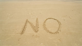 砂浜にNOと書かれたイメージ